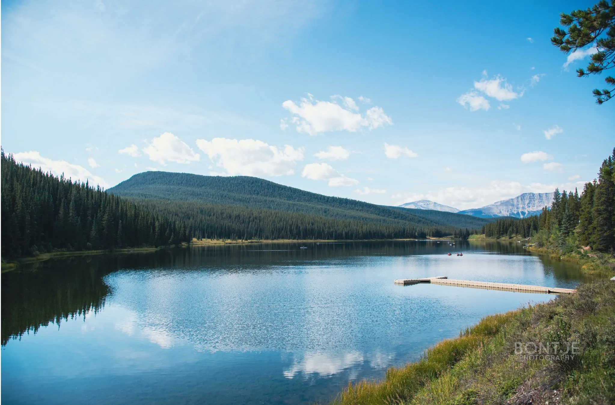 a lake with a dock and mountains in the background