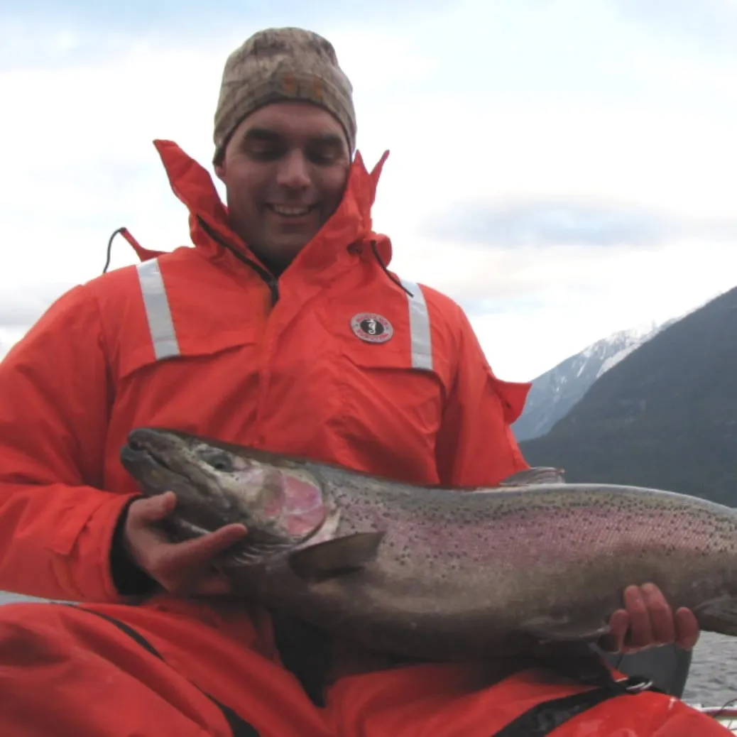 Daren Schwieger holding a huge fish that he just caught with the mountains in the background